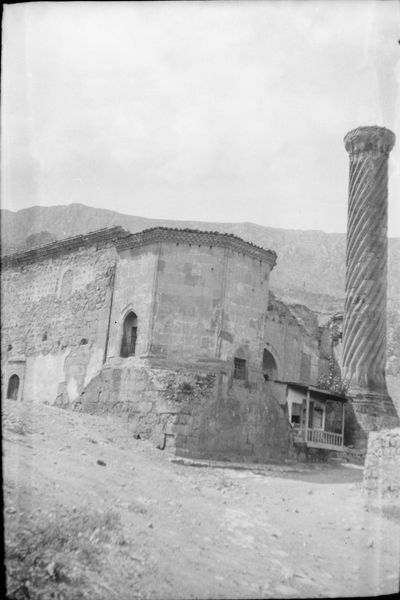 Harap haldeki cami ve sağda dönerek dolanan yivli taş minare; ortada sekizgen türbe gövdesi