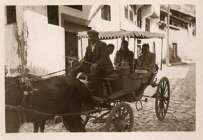 Saçaklı tenteli manda arabasında, bohçalarıyla hamama giden kadınlar; arnavut kaldırımlı Amasya sokağı