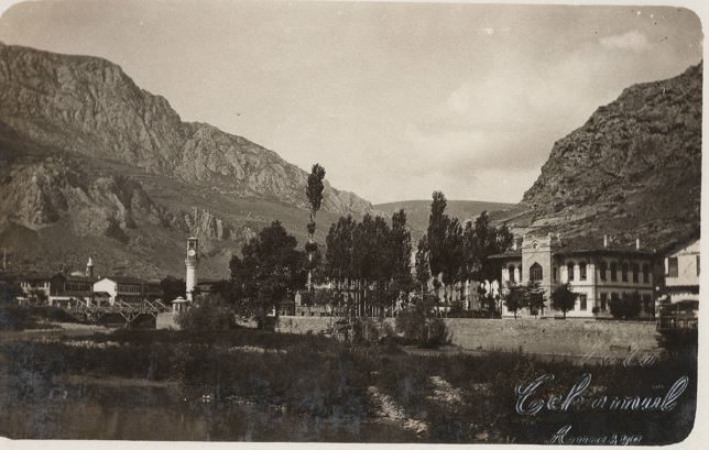 Solda ahşap köprü ve saat kulesi, sağda büyük beyaz Hükümet Konağı, arkada Harşena
