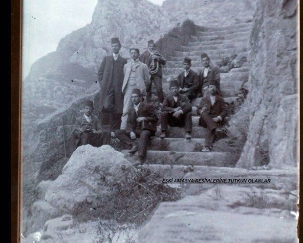 1895'te kayaya oyulmuş merdivende poz veren fesli ve ceketli bir grup