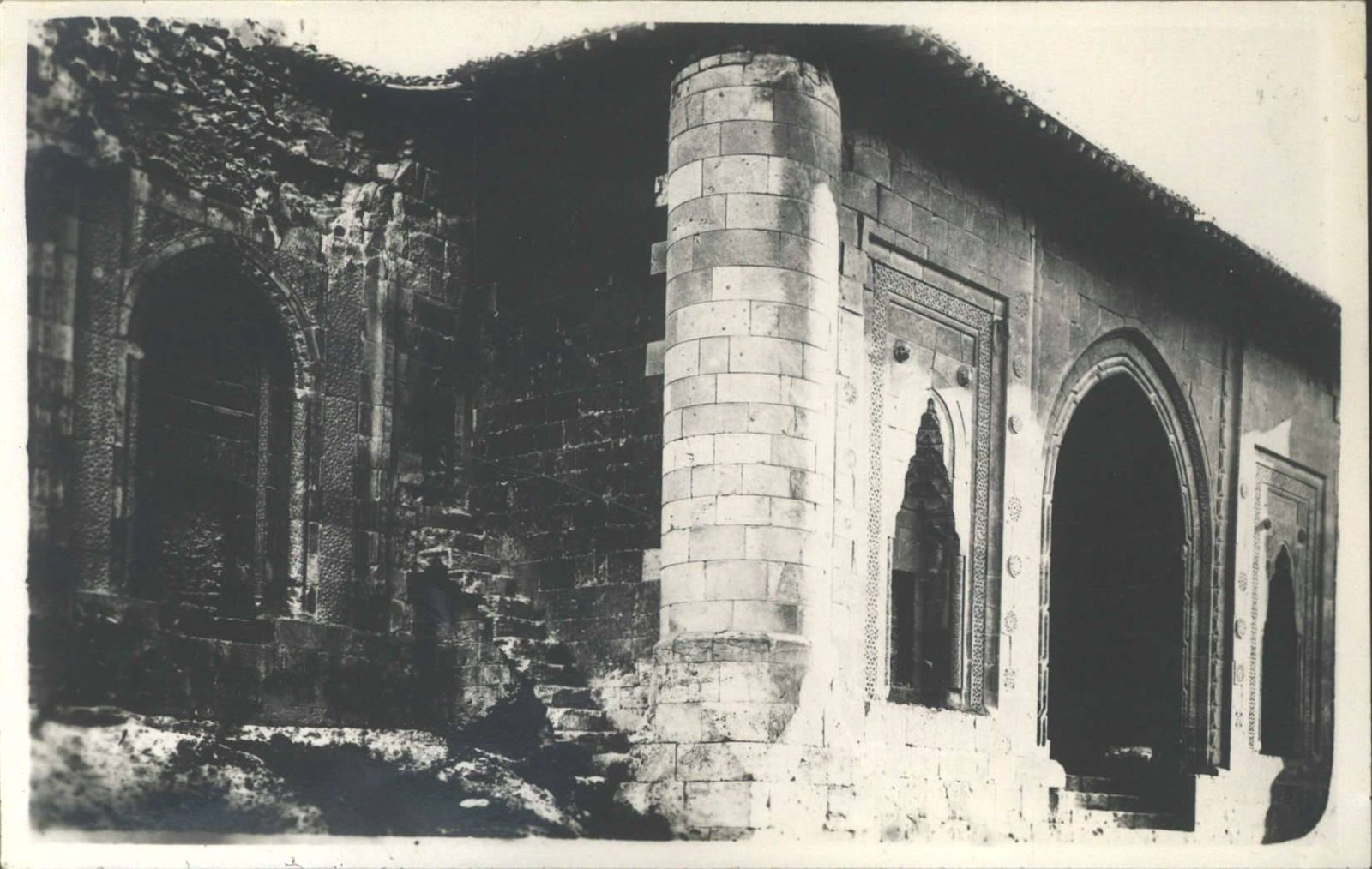 Solda kemerli nişli türbe, sağda Gökmedrese'nin eyvan cephesi; ikisinin arasında silindirik köşe payandası