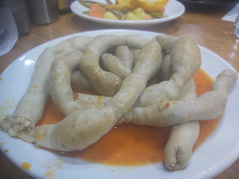 Kırmızı sosun içinde haşlanmış mumbar dolmaları.