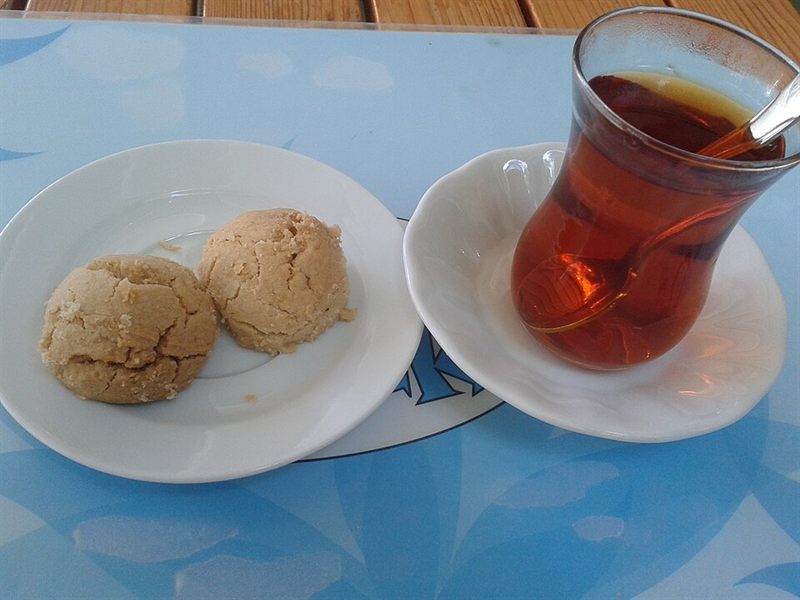Bir bardak çayın yanında tabakta iki un kurabiyesi.